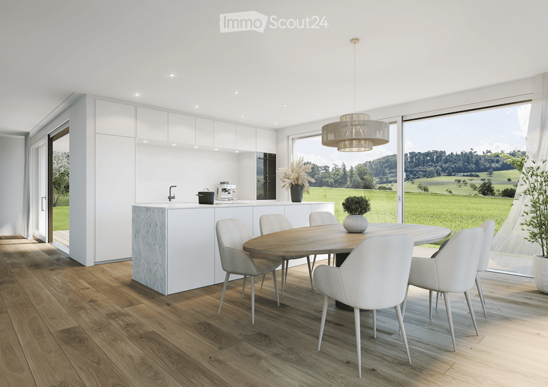 Furnished Room. Modern kitchen and dining area with white cabinets, a round wooden dining table surrounded by white chairs, a kitchen island, and a chandelier hanging from the ceiling. Large windows offer a scenic view of a green landscape.