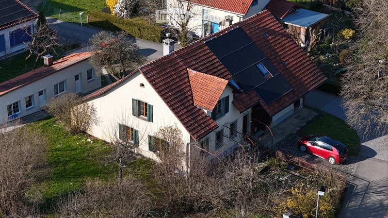 House. Aerial view of a two-story house with red-tiled roof, solar panels, and a red car parked in the driveway.