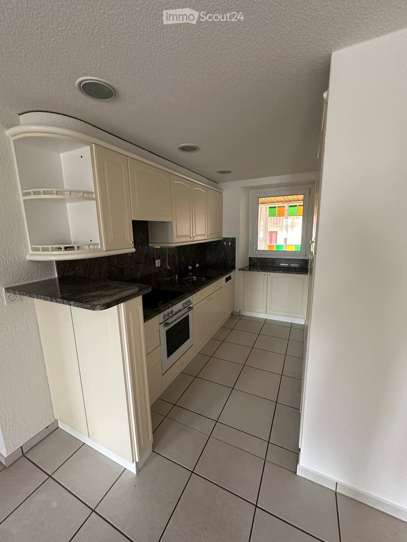 Kitchen. Modern kitchen with white cabinets, granite countertop, built-in oven, and tiled floor. Features a window with colorful glass panes.