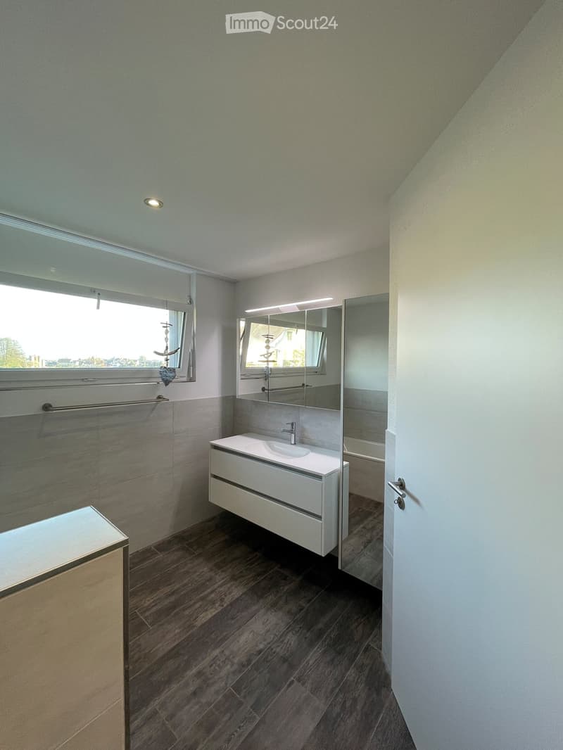 Bathroom with white sink, mirror, bathtub, window, wooden floor, white walls