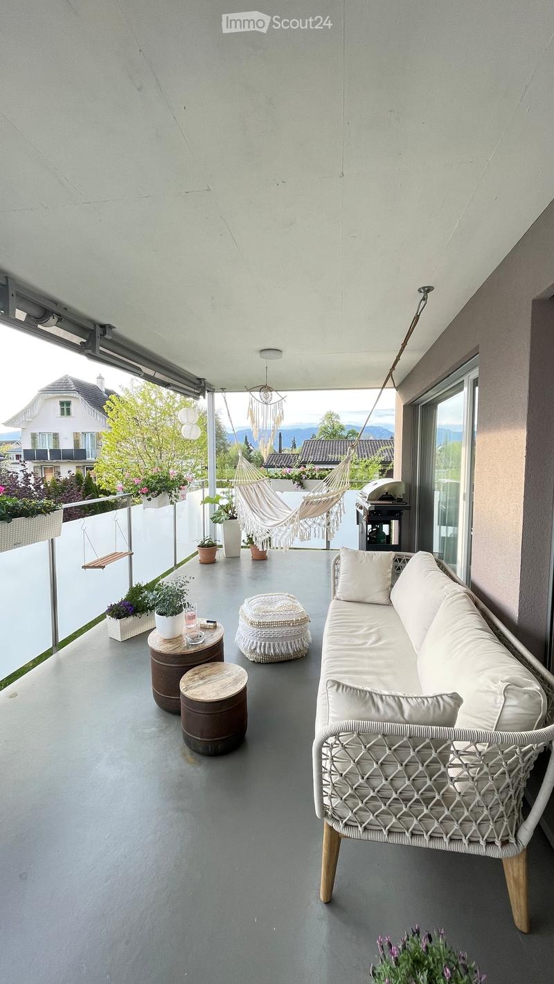 Balcony with white couch, hammock, wooden tables, potted plants, and a swing