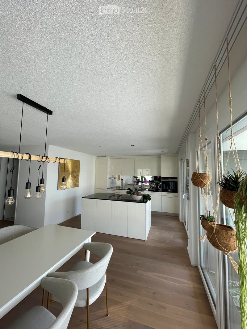 modern kitchen with island, white cabinets, black countertops, hanging plants, dining table, chairs