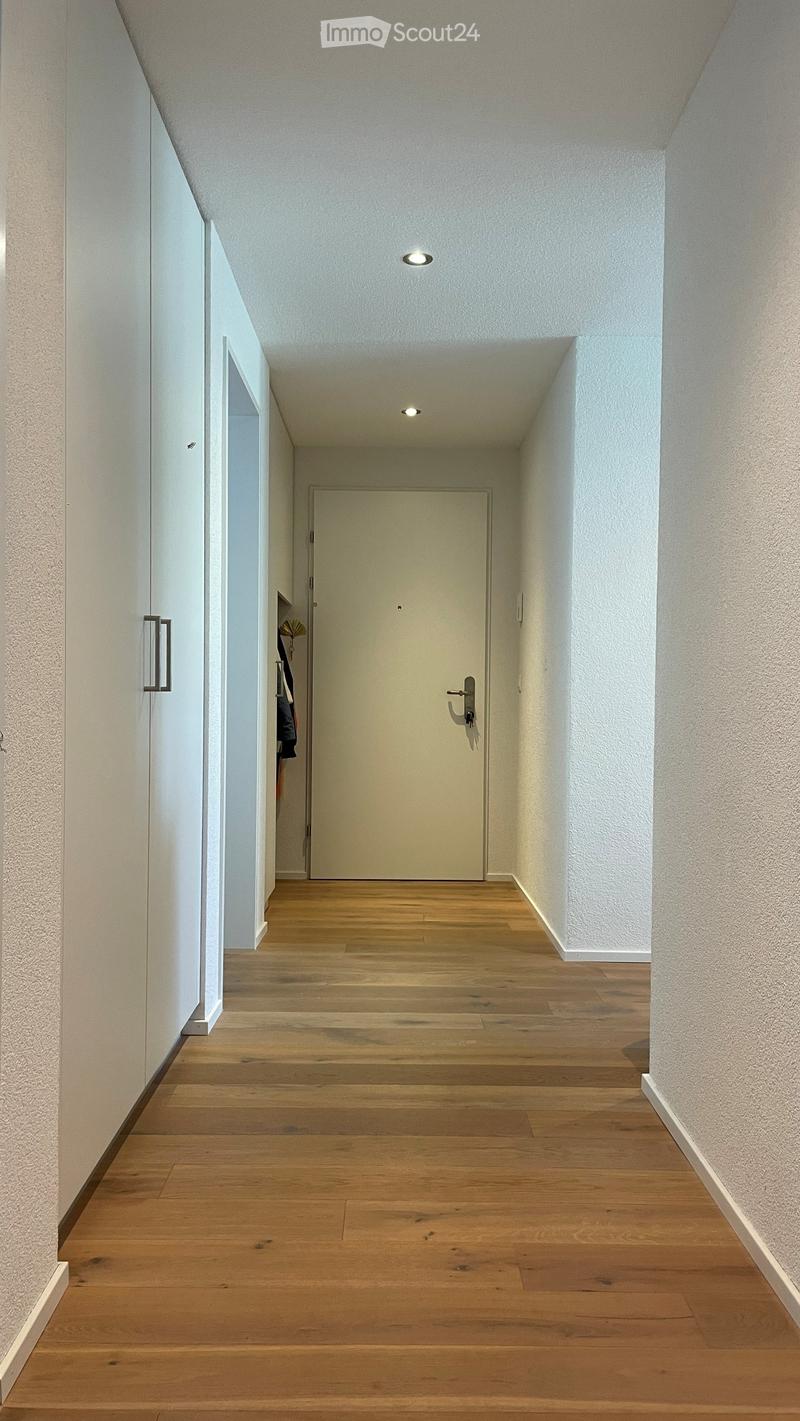 Empty hallway with wooden floor, white walls, and white door
