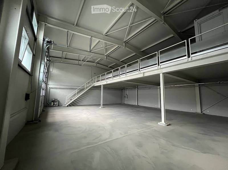 Unfurnished Room. Large, empty industrial-style space with concrete floor, metal beams, and a metal staircase leading to an upper level. No furniture or equipment present.