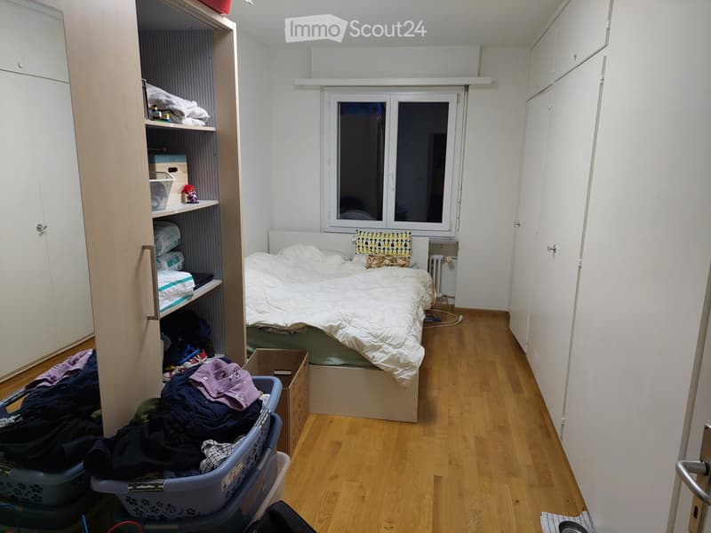 Bedroom. A small bedroom with a single bed, white wardrobe, shelves, and a laundry basket on the floor.