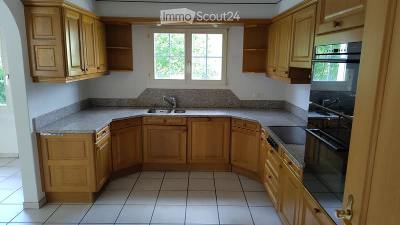 Kitchen. Bright kitchen with light wooden cabinets, granite countertops, and a double sink. The space features tiled flooring and ample natural light from a window.