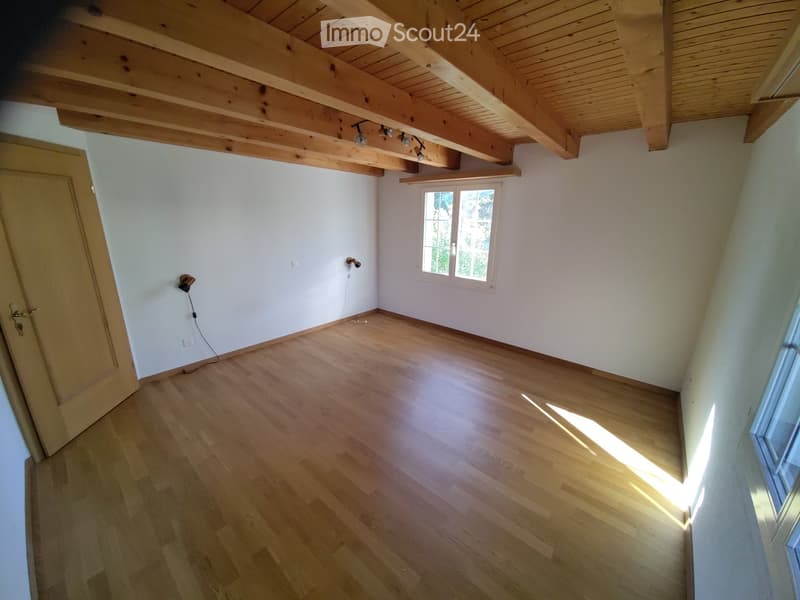 Unfurnished Room. Empty room with wooden flooring, white walls, and exposed wooden beams on the ceiling. Features a single window and a door.