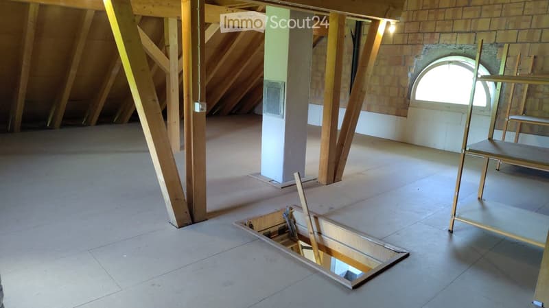 Unfurnished Room. Empty attic space with exposed wooden beams, concrete floor, and a partially open hatch leading to the ceiling below.