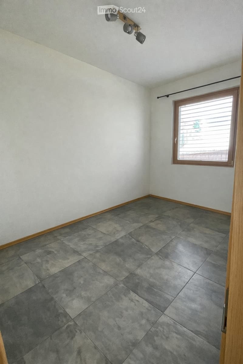 Unfurnished Room. Empty room with grey tiled floor, white walls, and a window with blinds. No furniture or equipment present.