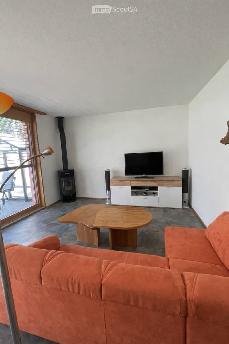 Living Room. Modern living room with a fireplace, orange sofa, wooden coffee table, TV on a white cabinet, and a floor lamp.