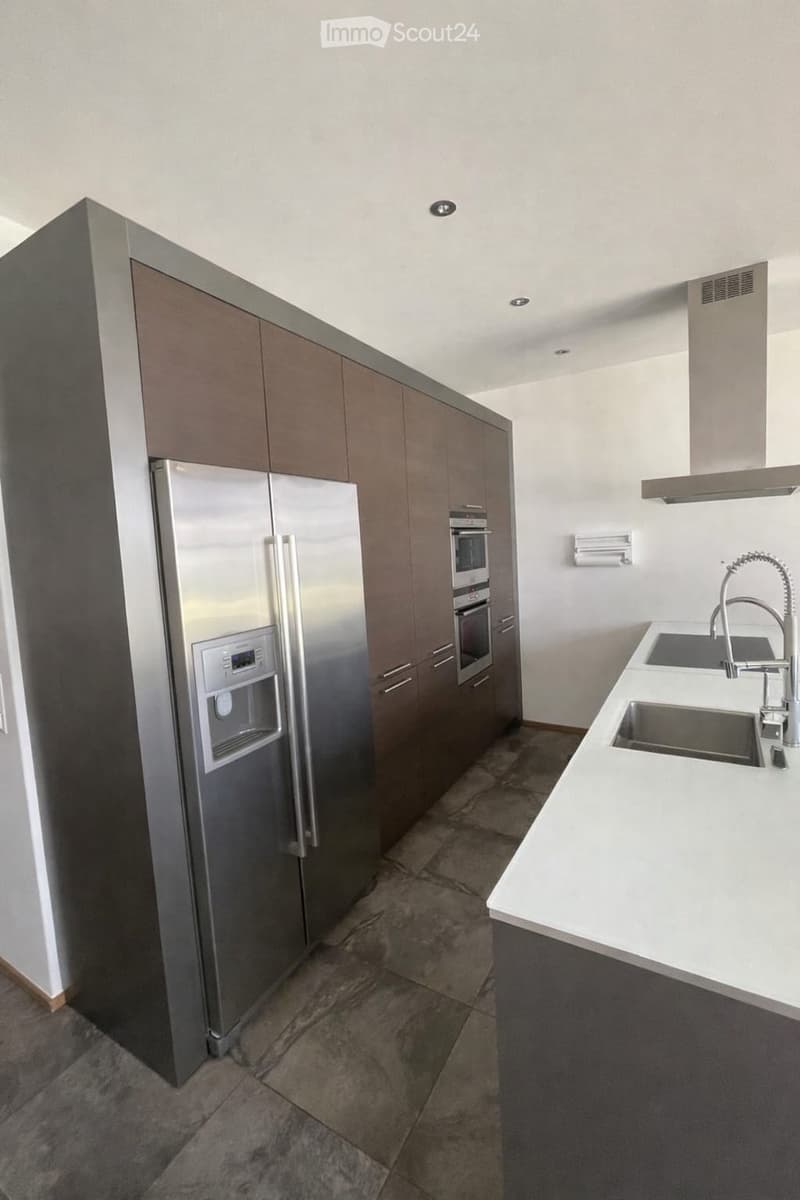 Kitchen. Modern kitchen with stainless steel refrigerator, built-in oven, white countertops, and a double sink with a modern faucet.