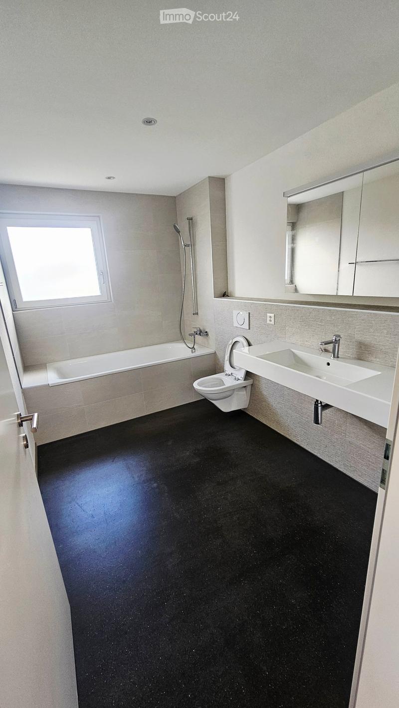 Bathroom. Modern bathroom with a black floor, white bathtub, toilet, sink, and mirror. Features a window and modern fixtures.