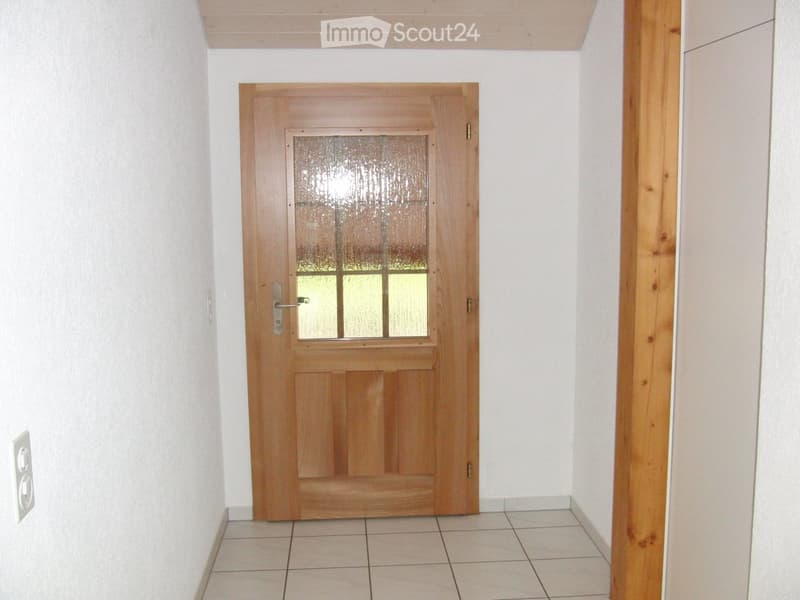 Corridor / Hallway. A narrow hallway with a wooden door featuring a frosted glass panel, white walls, and tiled flooring.