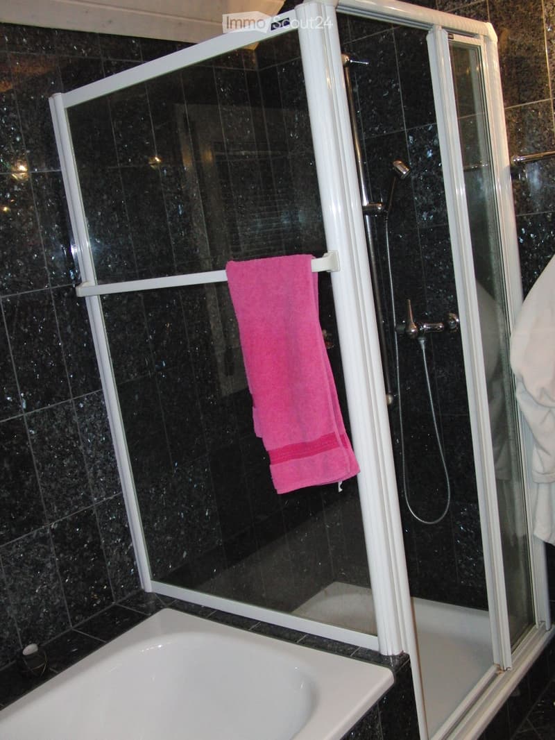 shower with glass door, bath tub, towel hanging on rail, tiled walls