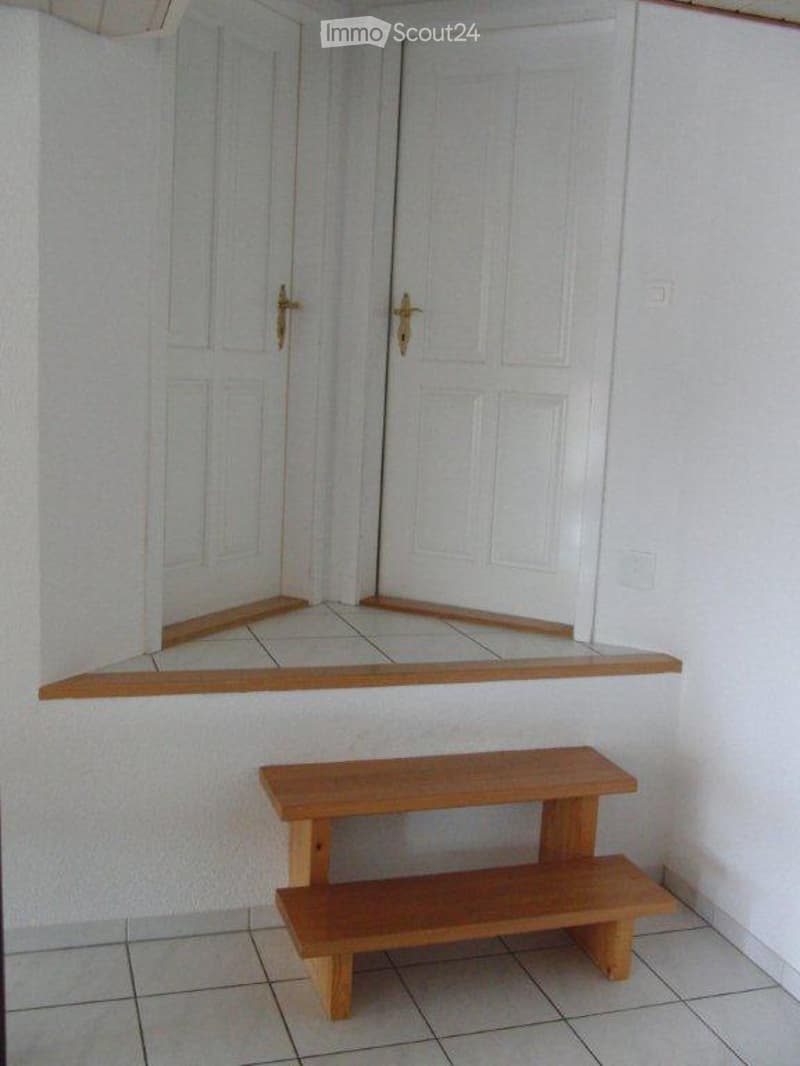 white walls, wooden bench, tiled floor, large arched windows with white doors