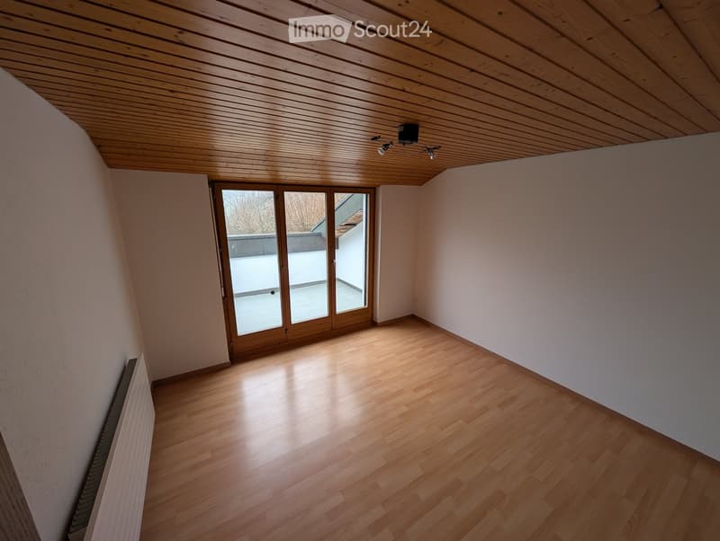 Unfurnished Room. Empty room with wooden flooring, white walls, and a large window with wooden frame leading to a balcony or terrace area.