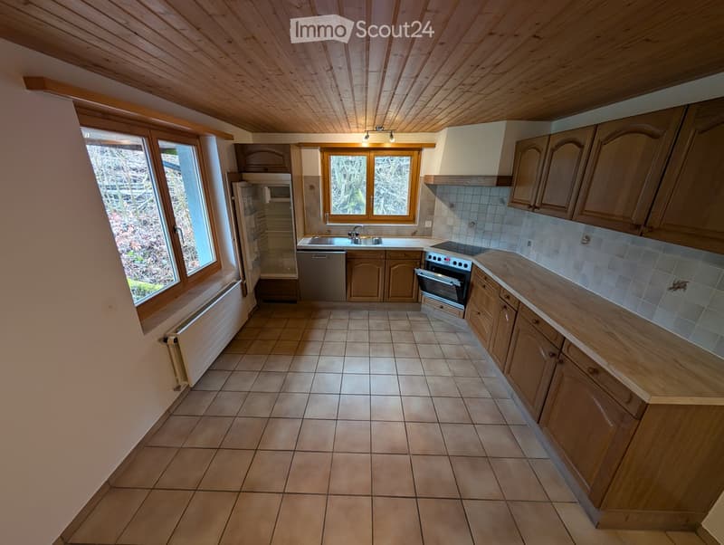 Kitchen. Bright kitchen with wooden cabinets, tiled floor, and stainless steel appliances including a refrigerator, dishwasher, and oven. Large windows provide natural light.