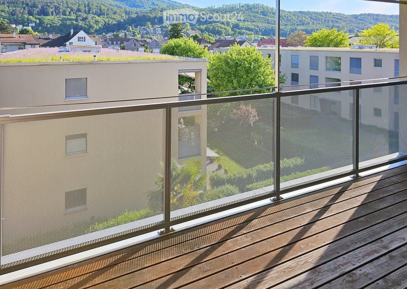 Balcony / Terrace. Balcony with wooden decking, metal railing, and scenic view of town and hills.