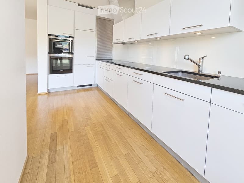 Kitchen. Modern kitchen with white cabinets, stainless steel sink, and built-in oven. Light wooden flooring and sleek countertops.