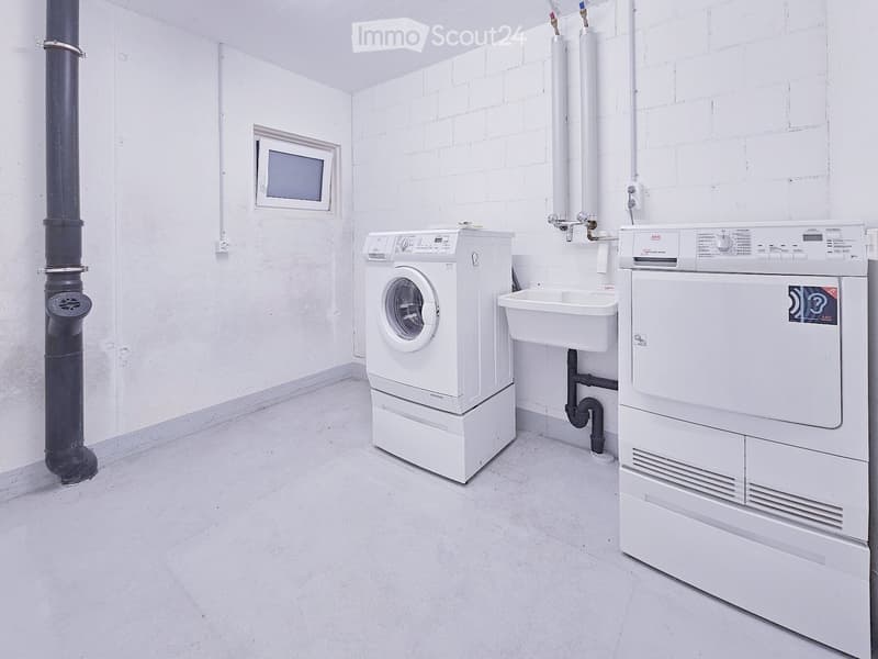 Bathroom. A small, clean bathroom with white brick walls, a washing machine, a dryer, and a sink.