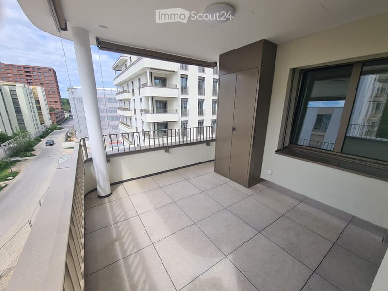 Balcony / Terrace. Balcony with tiled floor, metal railing, large window, and view of modern apartment buildings.