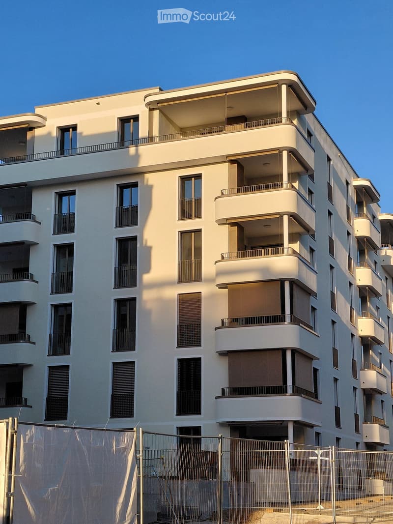 Building. Modern multi-story residential building with white facade, multiple balconies, large windows, and contemporary design.