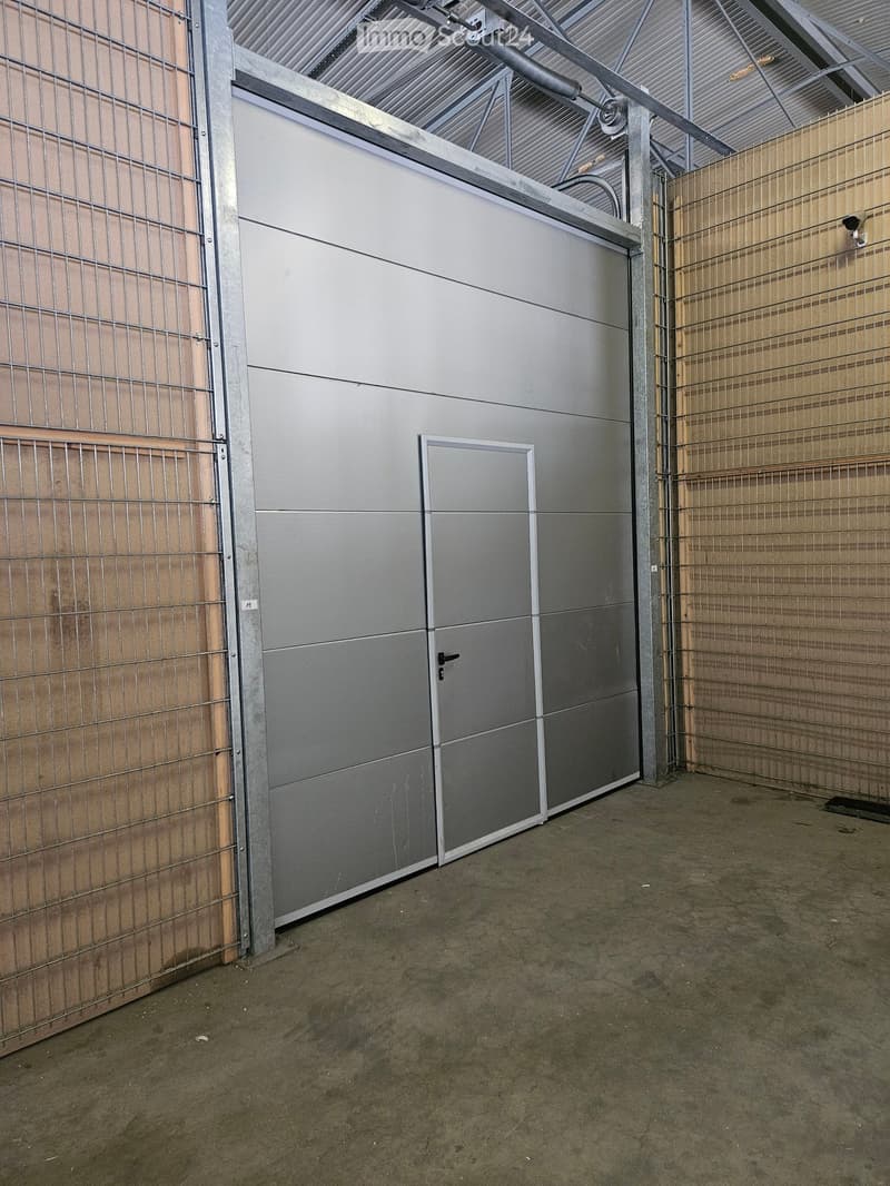 Garden / Outdoor Area. Empty outdoor area with a metal garage door, wooden fence, and metal framework, under a corrugated metal roof.