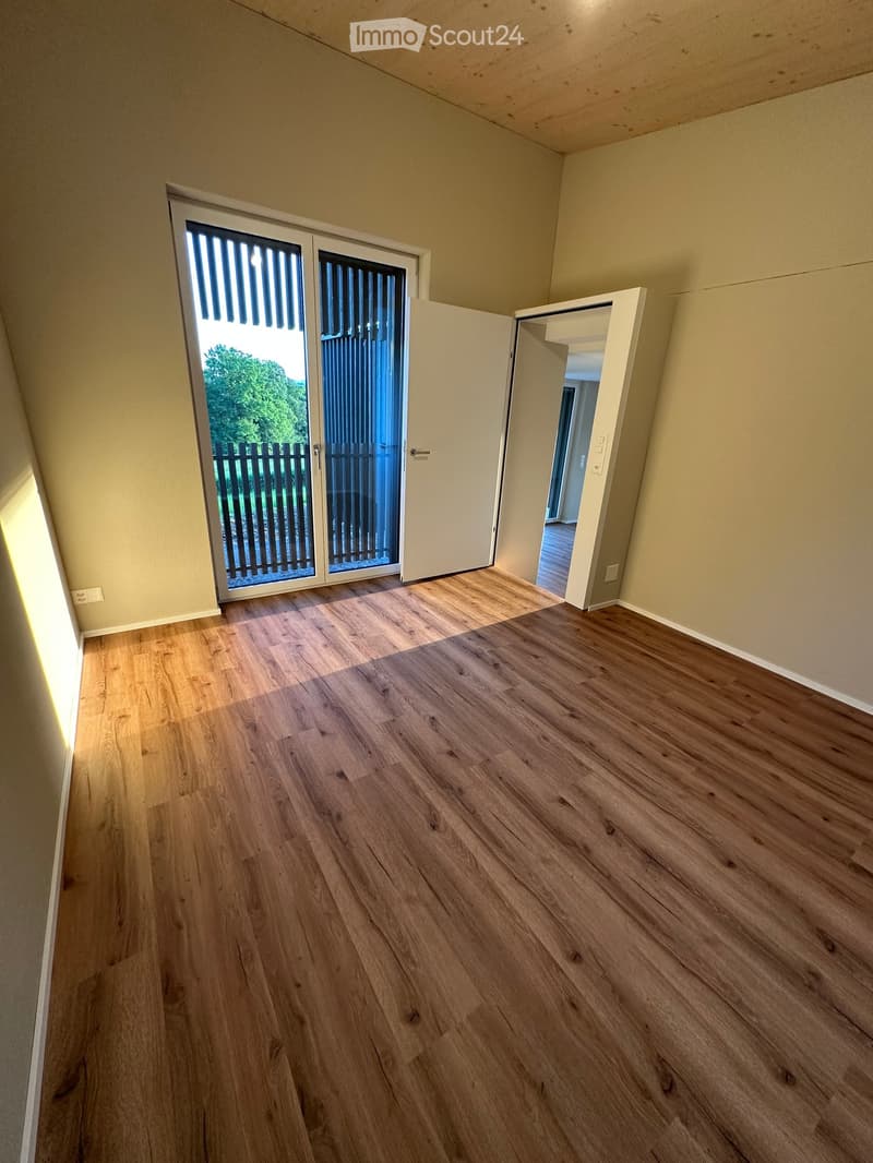 Unfurnished Room. Empty room with wooden flooring, white walls, and a sliding glass door leading to an outdoor area.
