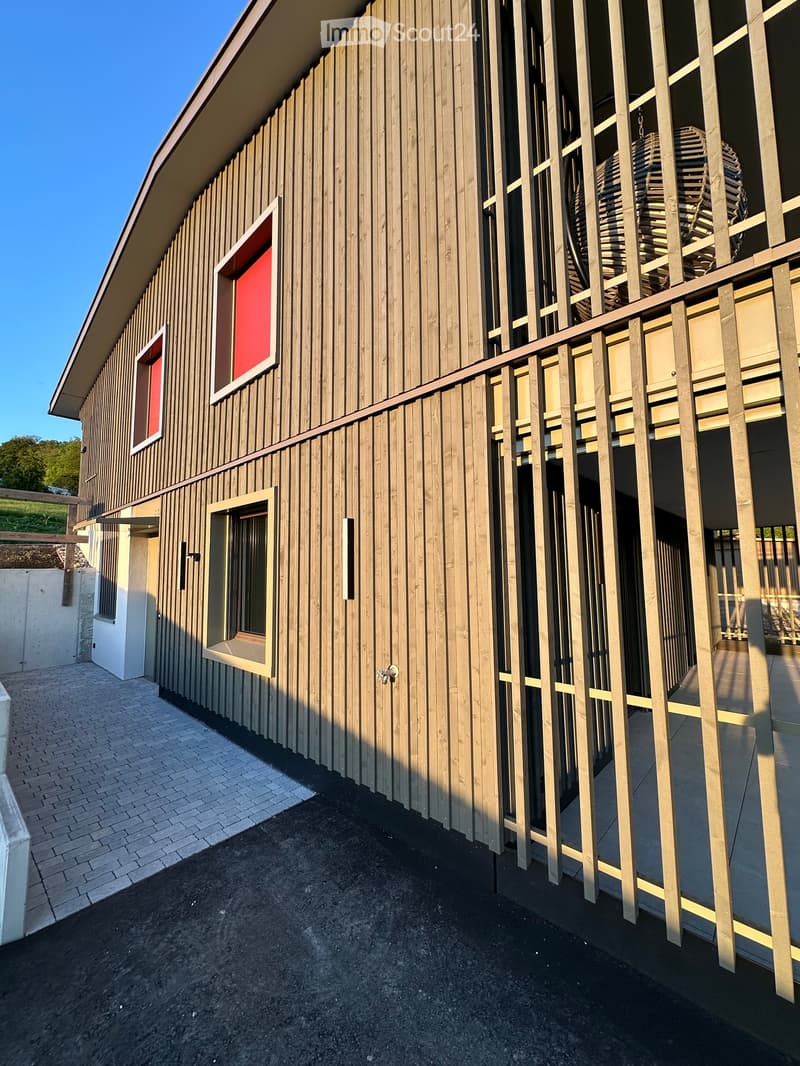 Building. Modern wooden building with a raised ground floor, featuring a balcony with wooden railings and a staircase leading up.