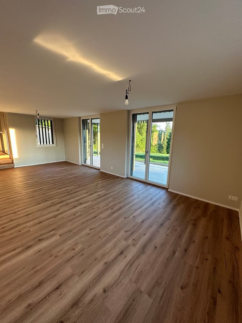 Unfurnished Room. Empty room with wooden flooring, large sliding glass doors, and natural light from windows.