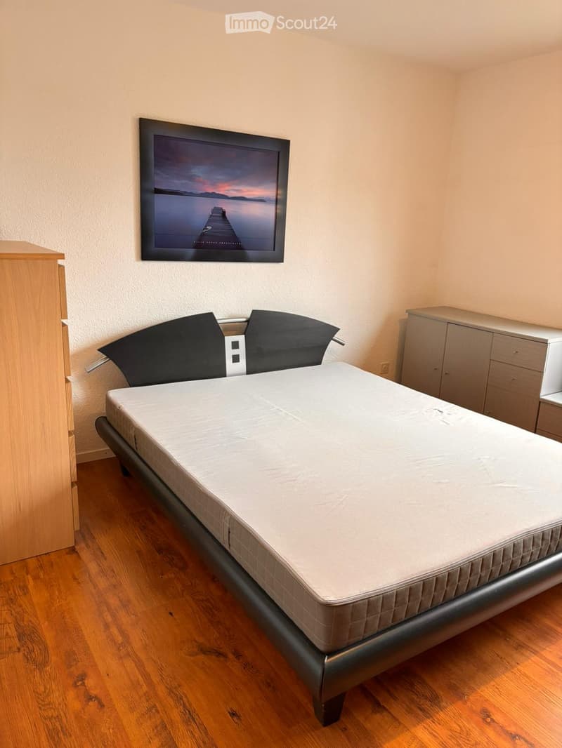 Bedroom. A neatly arranged bedroom with a single bed, a nightstand, and a large screen mounted on the wall.