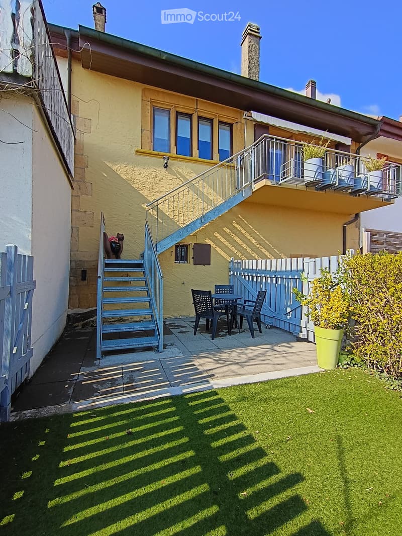 Garden / Outdoor Area. Garden area with green artificial grass, patio furniture including chairs and a table, a staircase leading to a balcony, and a small potted plant.