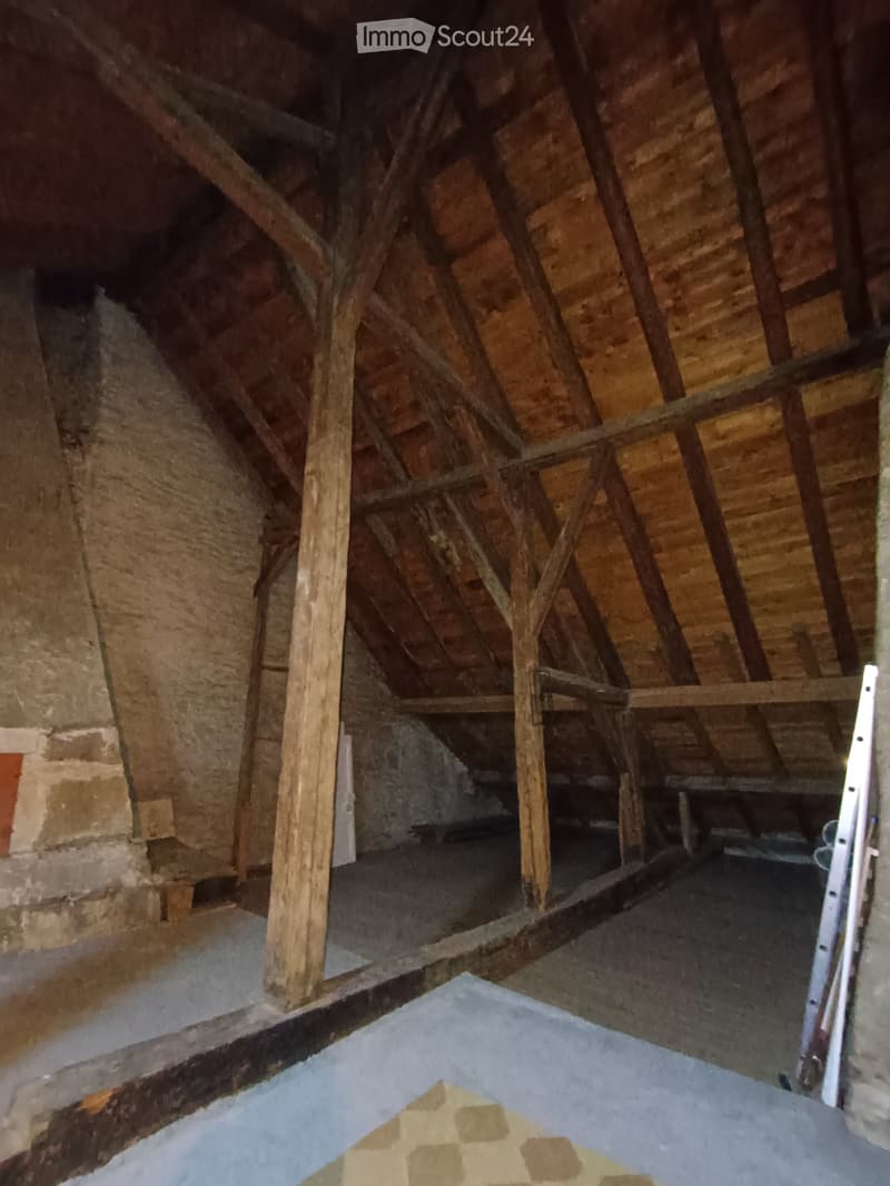 Unfurnished Room. Empty attic space with exposed wooden beams, stone walls, and a concrete floor. No furniture or equipment present.