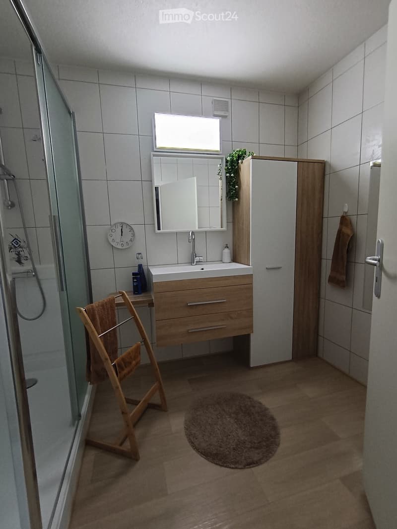 Bathroom. Modern bathroom with a wooden vanity, white sink, mirror, towel rack, and a shower area with a glass door.