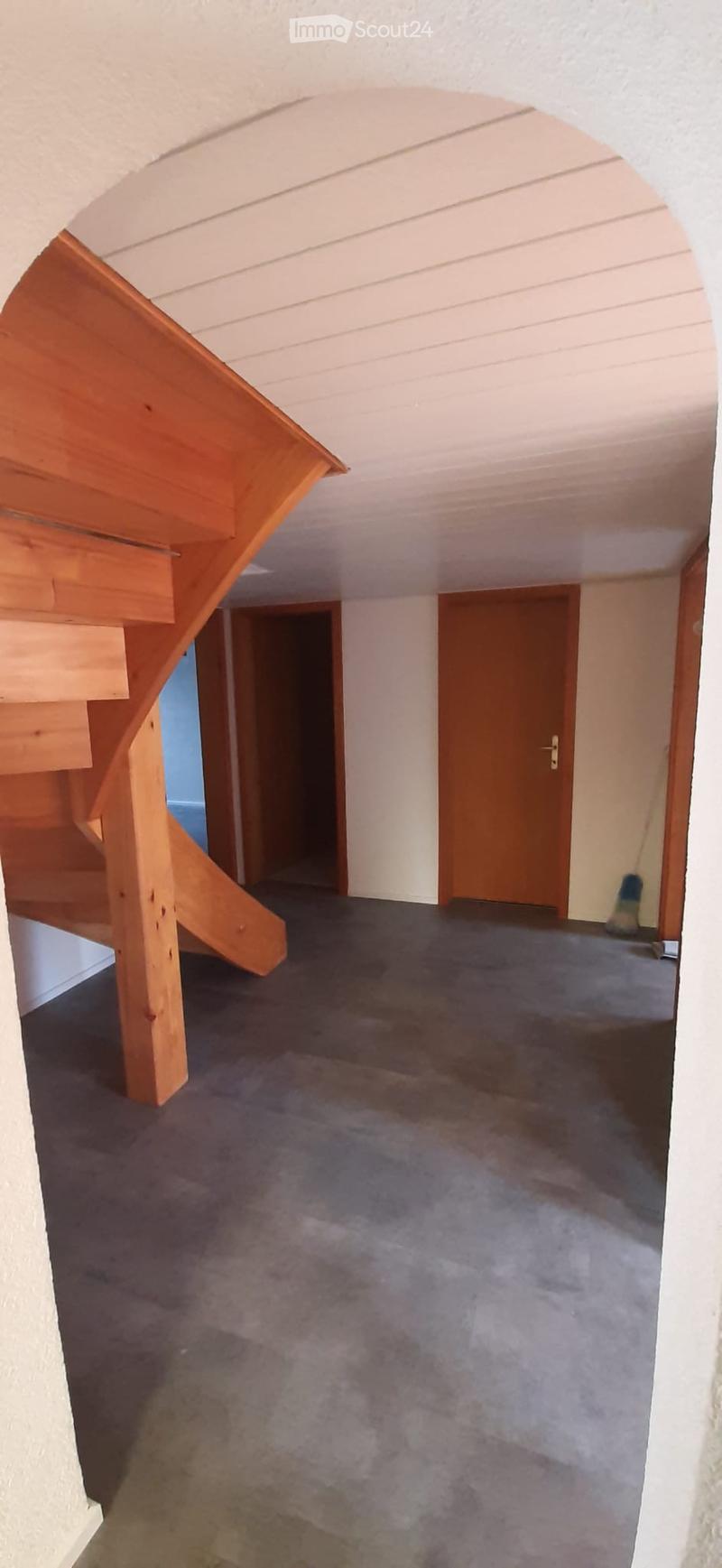 Corridor / Hallway. Empty hallway with wooden staircase, carpeted floor, and closed wooden doors leading to other rooms.