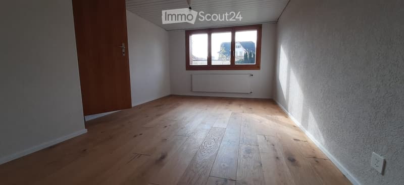 Unfurnished Room. Empty room with wooden flooring, white walls, a window with wooden frame, and a radiator below the window. No furniture or equipment present.