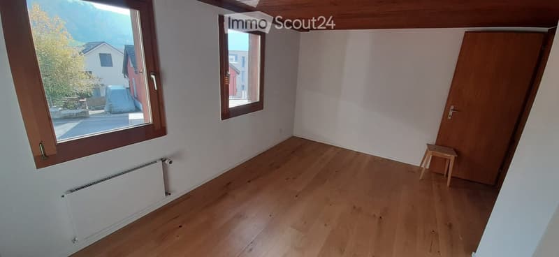 Unfurnished Room. Empty room with wooden flooring, white walls, large windows, and a small wooden stool near the door.