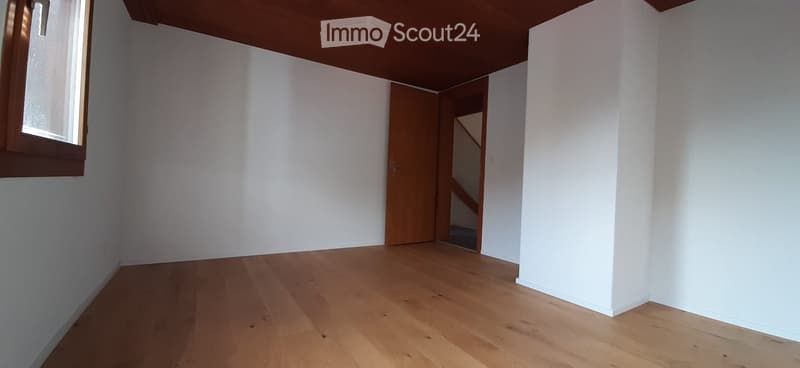 Unfurnished Room. Empty room with white walls, wooden floor, and a wooden door leading to a staircase.