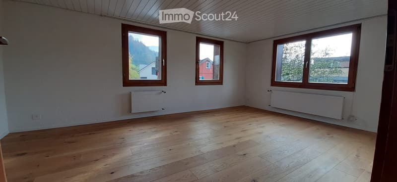 Unfurnished Room. Empty room with wooden flooring, white walls, and three windows with wooden frames. Radiators are mounted on the walls.