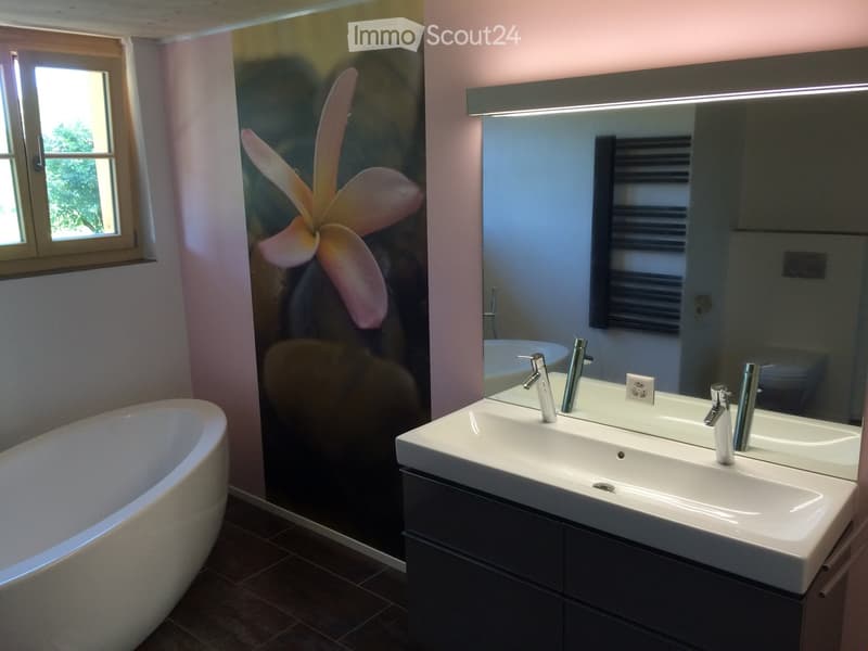 Bathroom. Modern bathroom with a freestanding bathtub, double sink vanity with sleek faucets, large mirror with integrated lighting, and a decorative floral wall mural.