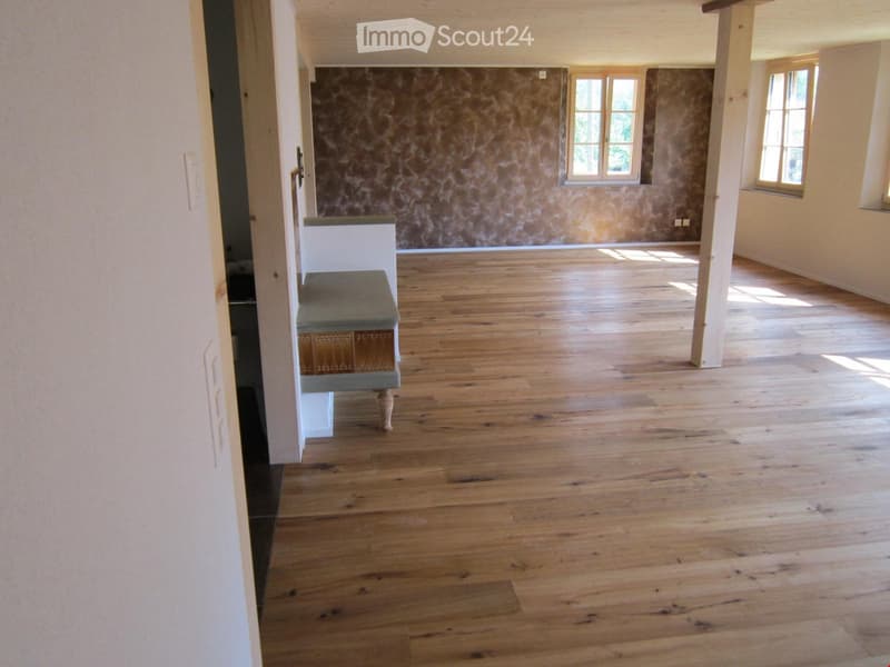 Unfurnished Room. Empty room with wooden flooring, white walls, and large windows allowing natural light. A small bench is visible near the doorway.