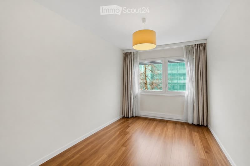 Unfurnished Room. Empty room with wooden flooring, white walls, large window with curtains, and a hanging light fixture.
