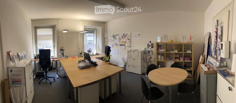 Office space with desks, chairs, shelves, and a round meeting table.