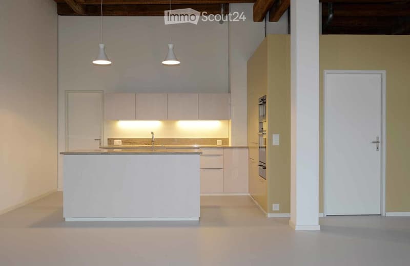 Unfurnished Room. Empty kitchen area with white cabinets, a central island, and pendant lights. No furniture or appliances are present.