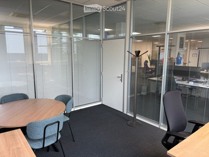modern office with glass walls, round table, chairs, coat rack, desk, office equipment