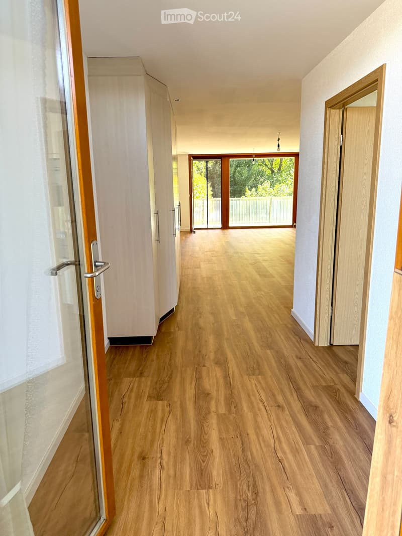 large hallway with wooden floors, glass sliding doors, tall windows with balconies