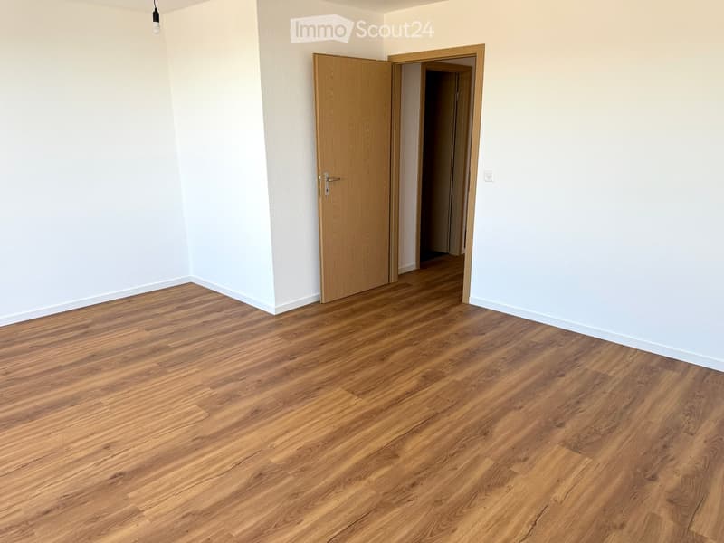 Empty room with wooden floors, white walls, two doors and a window.