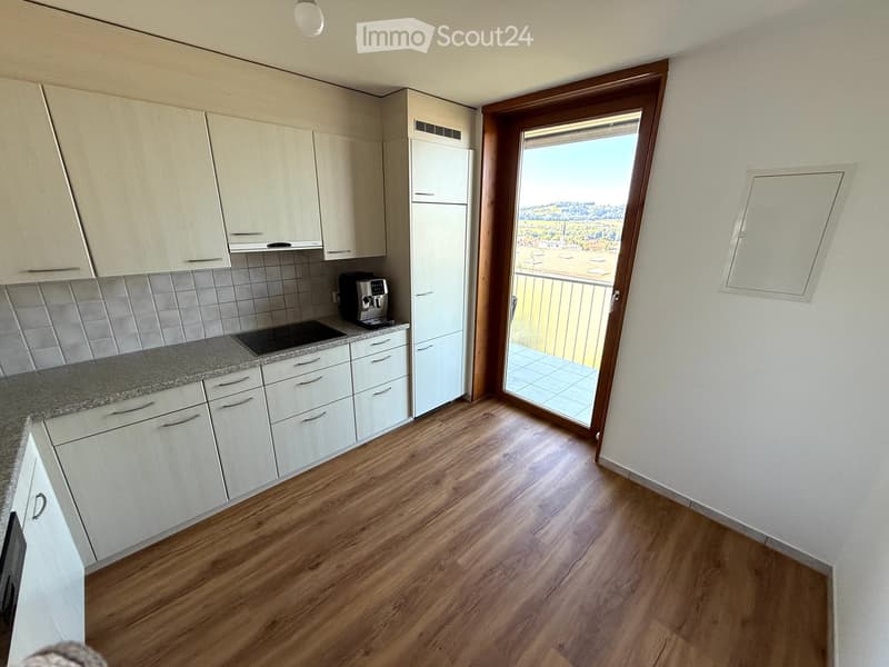 White cabinets, tiled backsplash, granite countertop, black appliances, balcony access, scenic view