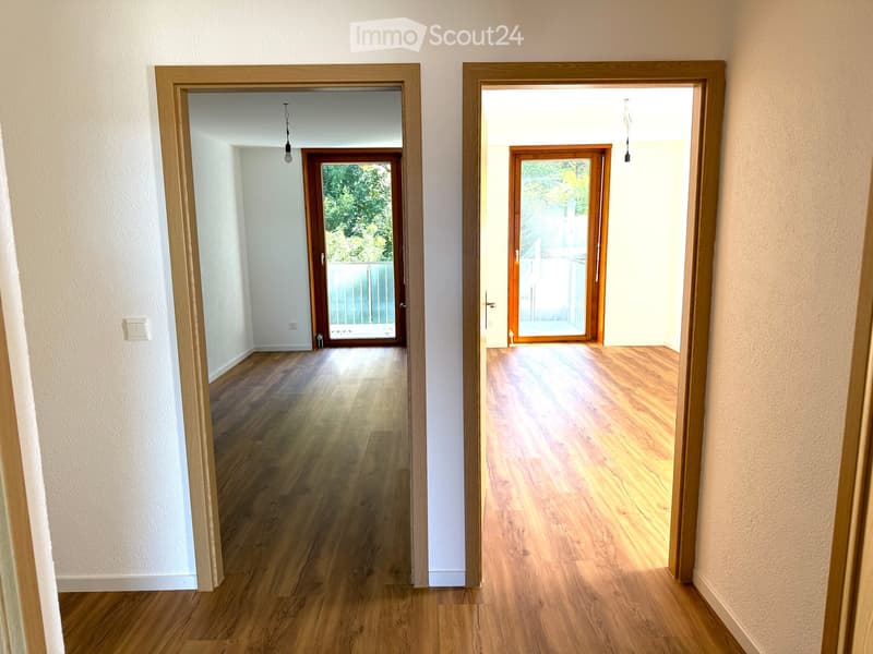 Open room with wooden floor and sliding glass doors leading to balcony