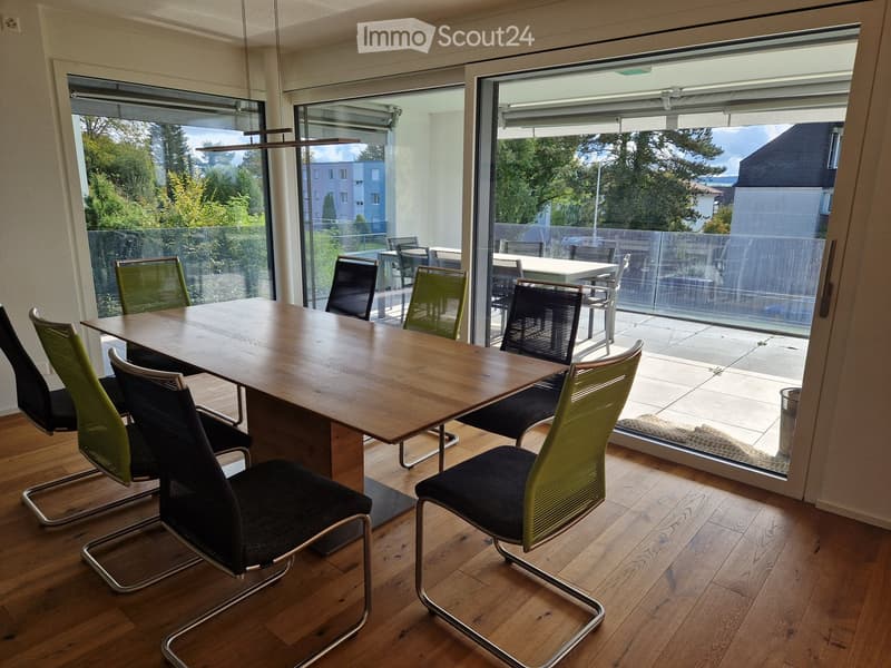 dining table with chairs, large windows, balcony with glass railings, modern chairs, wooden flooring